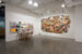 Photo of a partial exhibition view of "Setting the Table". On the right, the Folie culture installation and documents from the collection are visible. The main subject of the photo, on the right, is 'Vieux buffet' (2011-2014), work by Marc-Antoine K. Phaneuf's, an all-over mural of 300 vintage recipe books, whose many colours contrast with the white of the exhibition room walls and the grey of the concrete floor.