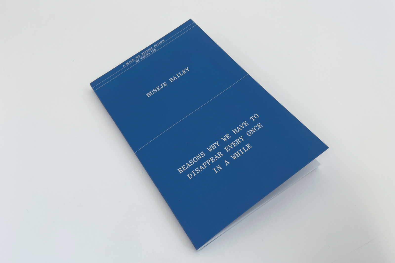 Photo of the chapbook by Yaniya Lee. The minimalist blue cover is marked by the title of the book in white. Written in capital letters, the title reads "A Black art history project by Yaniya Lee" at the top of the cover. In the centre, it says "Buseje Bailey" in larger font. Finally, at the bottom of the cover, it written in medium font "reasons why we have to disappear every once in a while". The blue cover contrasts with the clarity of the uniform white background.