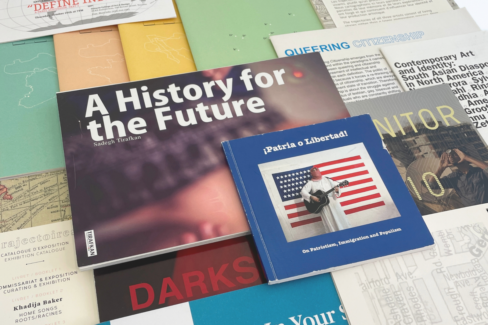 Square colour photograph showing many documents of various colours and sizes placed on top of each other. We can read a few titles: "A History for the Future", "¡Patria o Libertad!" and "Queering Citizenship"