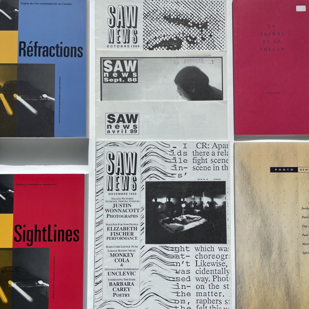 Colour photograph showing a number of different documents layed out on a white background. We see copies of "Saw News" and of "Sightlines" magazine, amongst others.