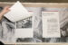 Colour photograph of two spiral-bound documents placed on top of a black and white image of a duvet. The one on the left is being flipped open and we see a black and white image of a stool. The one on the right has the description of the project.